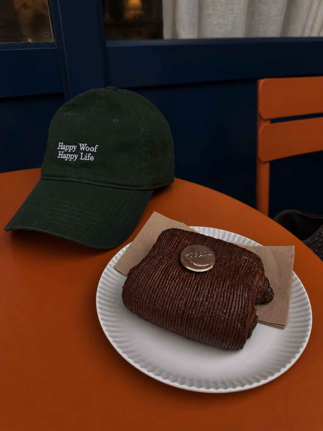 A green Happy Woof, Happy Life CHILLI cap on an orange café table